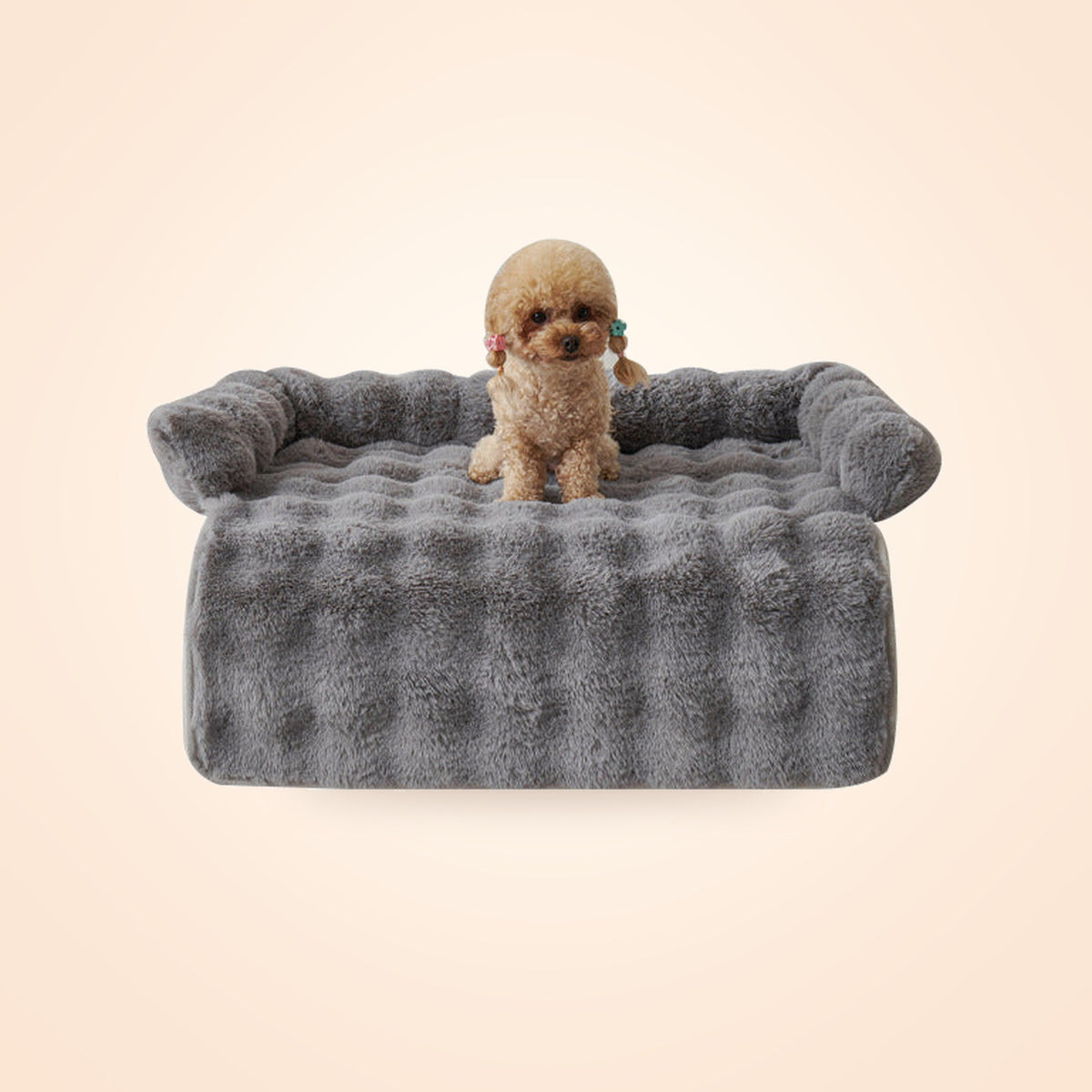 Grey plush couch pet bed with bolster sides and a small poodle sitting on it, on a warm cream background