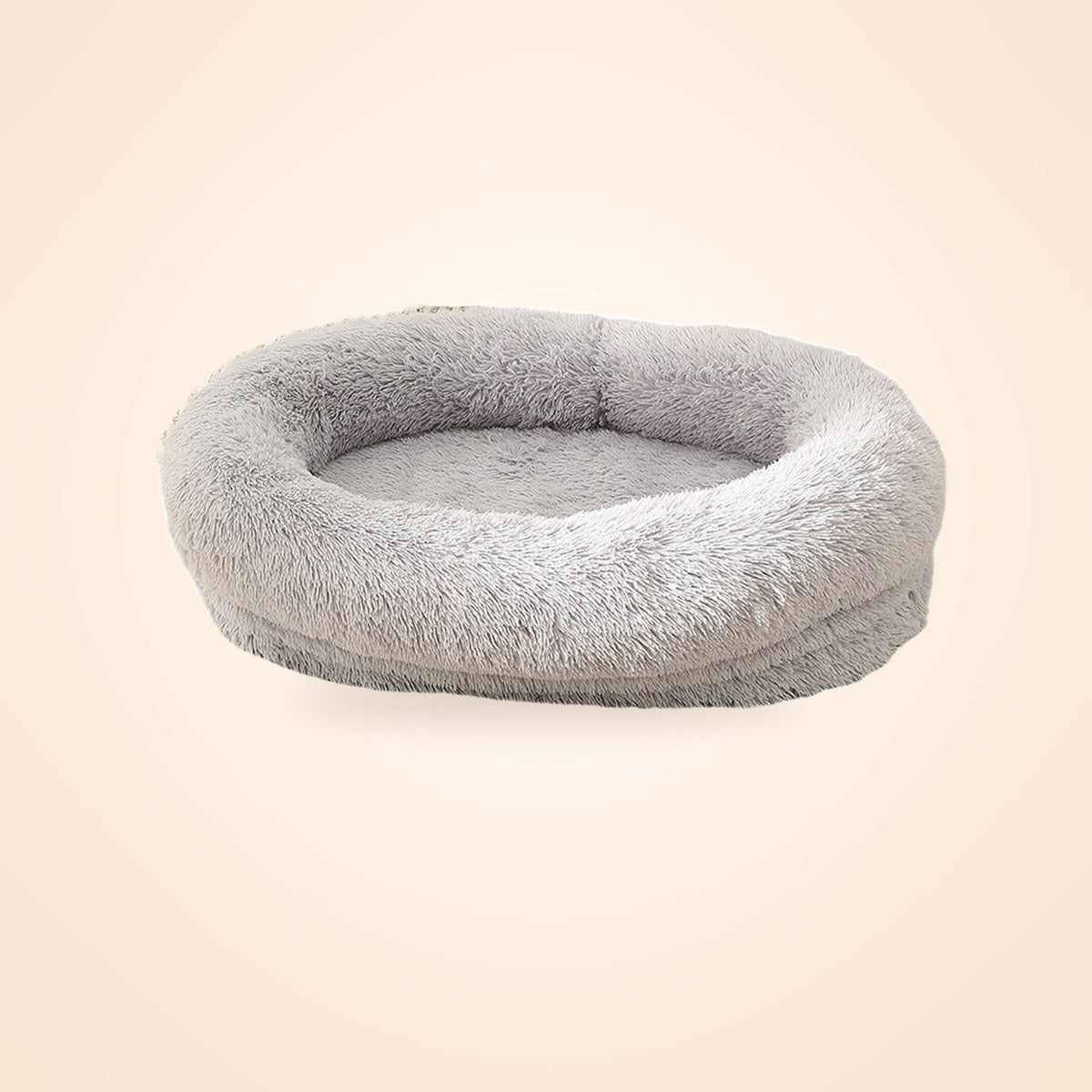 Grey plush oval donut pet bed with a raised rim, on a warm cream background