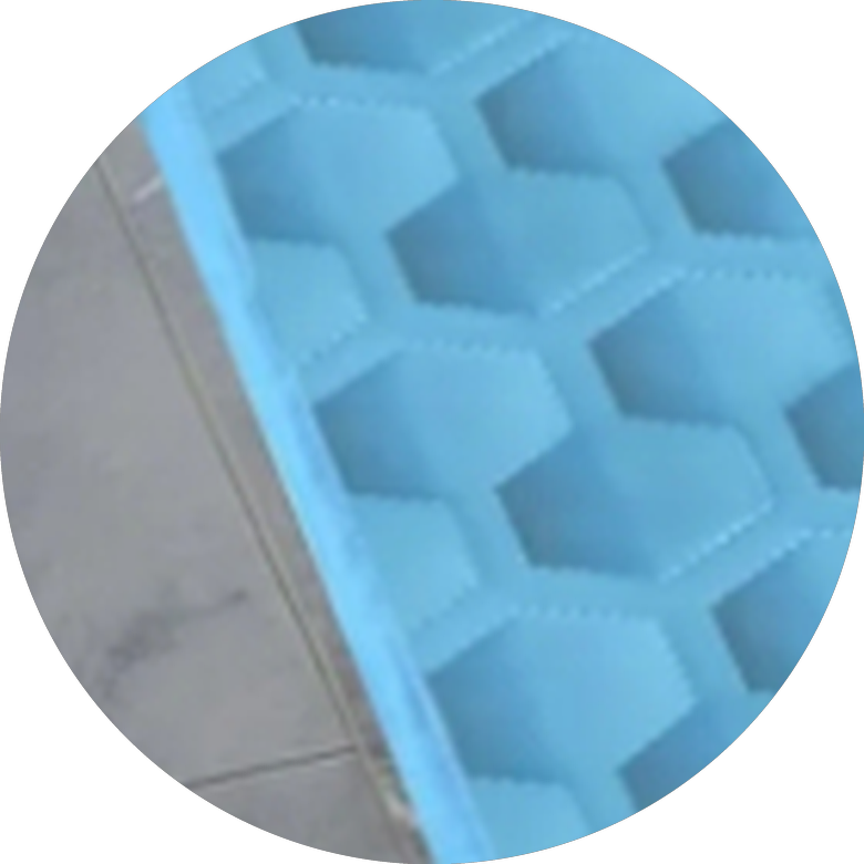 Close-up of the cooling mat lying flat on a tiled floor, showing how thin the quilted pad is