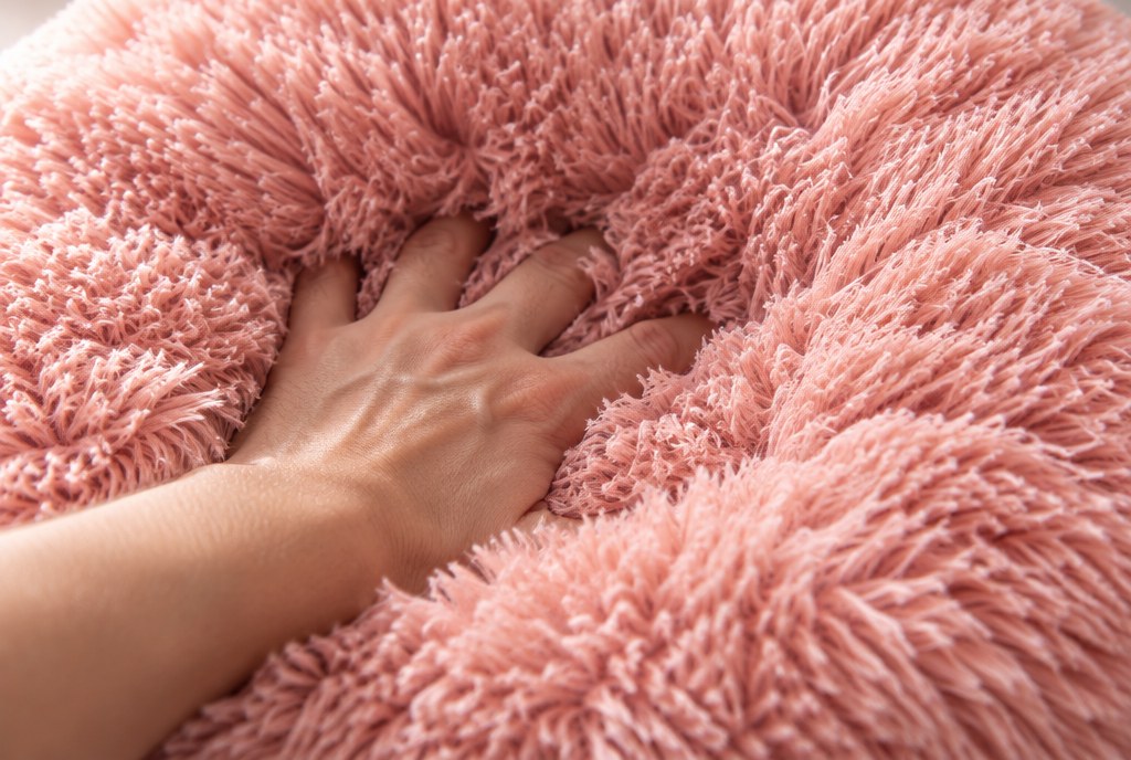 A hand sunk past the knuckles into the long faux fur of the bed